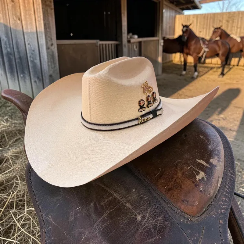 Sombrero vaquero claro con pines de caballo y una placa con la palabra Peruano sobre una cinta blanca y negra, apoyado en una silla de montar